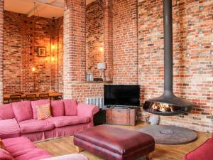 a living room with pink furniture and a brick wall at Windy Mundy Farm in Shrewsbury