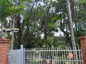 une clôture blanche avec une porte blanche et des arbres dans l'établissement Recanto dos Passaros, à Socorro