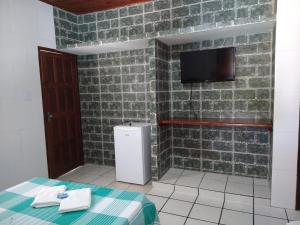 a room with a small refrigerator and a tv on a brick wall at Pousada Dos Arcos in Jacumã