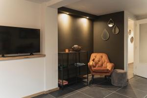 un soggiorno con sedia e TV a schermo piatto di Vakantie-appartement Oppe Donck met sauna a Posterholt