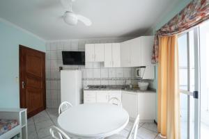 a kitchen with a white table and a white refrigerator at Pousada Cantinho Sonhado in Bombinhas