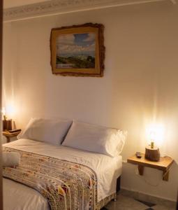 a bedroom with a bed and a painting on the wall at NOGAL HOSTEL in Pereira +27 photos