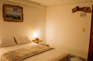 1 dormitorio con 1 cama y 1 lámpara en la pared en NOGAL HOSTEL, en Pereira