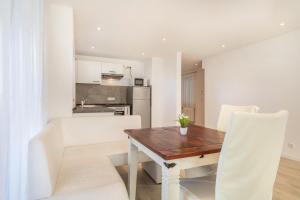 eine Küche und ein Esszimmer mit einem Holztisch und weißen Stühlen in der Unterkunft Ferienwohnung Gartenstraße in Lindau-Bodolz