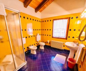 a yellow bathroom with two toilets and a shower at Hotel Valgioconda in Sappada