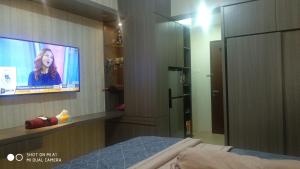 ein Schlafzimmer mit einem TV und einem Bett in einem Zimmer in der Unterkunft Apartemen Riverview Residence Jababeka at KiNGDOM Rent Apartment Solution in Cikarang