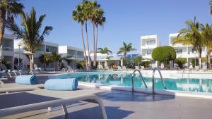 
a beach with a pool, chairs, and a pool table at Oasis Lanz Beach Mate in Costa Teguise
