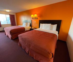 2 camas en una habitación de hotel con paredes de color naranja en Antilley Inn, en Abilene