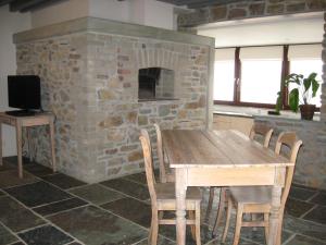 een keuken met een houten tafel en een stenen open haard bij Le Fournil d Andrimont in Stoumont
