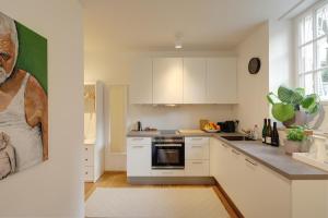a kitchen with white cabinets and a painting on the wall at Boutique Apartments Freiburg - Elsa in Freiburg im Breisgau