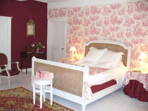 ein Schlafzimmer mit einem weißen Bett mit rosafarbener Blumentapete in der Unterkunft Château des Lutz in Daon