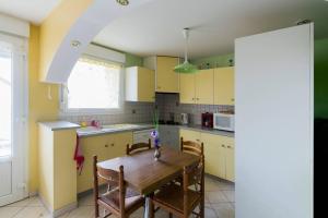 cocina con mesa de madera y armarios amarillos en Le Trèfle d'Or en Gérardmer