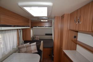 a small room with a bed and a window in a trailer at Mietwohnwagen Samson Fehmarn in Fehmarn