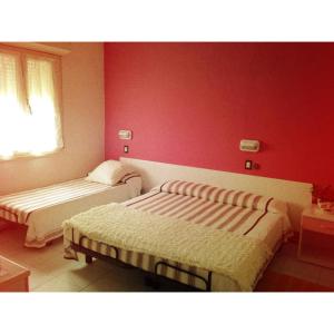 een slaapkamer met 2 bedden en een rode muur bij Hotel Zenit in Riccione