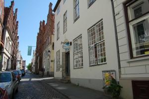 una calle con edificios y coches estacionados en una calle adoquinada en Jugendherberge Lübeck Altstadt, en Lübeck