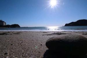 una playa de arena con el sol brillando sobre el océano en Kamogawa Shokudo - Vacation STAY 15119v, en Kamogawa