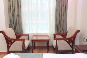 Habitación con 2 sillas, mesa y ventana en Vickmark Hotel, en Nakuru