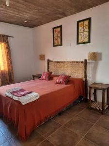 um quarto com uma cama com uma colcha vermelha em La Posada de la Calandria em Purmamarca