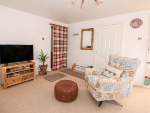 a living room with a chair and a flat screen tv at Fairfield Cottage in Lincoln