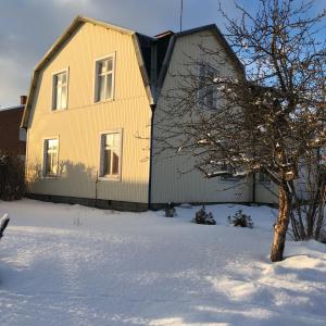 una casa amarilla en la nieve con un árbol en Parkgatan villa, en Krylbo