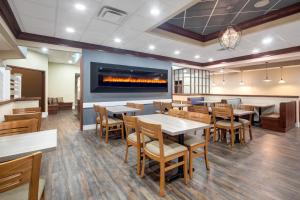 a dining room with tables and chairs and a fireplace at Travelodge Hotel by Wyndham Sudbury in Sudbury