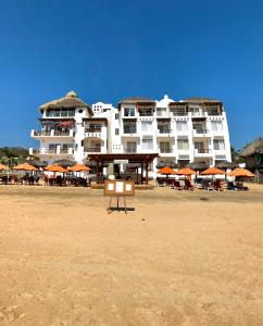 a large white building on a beach with umbrellas at Hotel Estrella de Mar in Zipolite