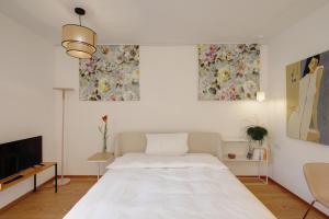 Boutique Apartments Freiburg - Eva في فريبورغ ام بريسغاو: غرفة نوم بيضاء مع سرير وتلفزيون