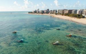 three boats in the water next to a beach at Grande Apartamento Beira-Mar 2/4 Pajuçara in Maceió