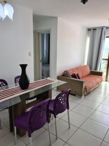 a living room with purple chairs and a table and a couch at Grande Apartamento Beira-Mar 2/4 Pajuçara in Maceió +16 photos