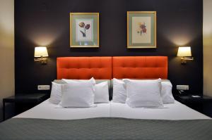 a bedroom with a bed with an orange headboard and white pillows at San Gil in Seville