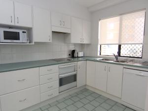 a kitchen with white cabinets and a sink and a microwave at The Breakers 8 in Forster