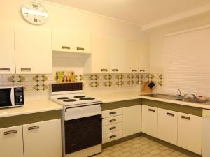 a kitchen with white cabinets and a stove top oven at The Breakers 10 in Forster