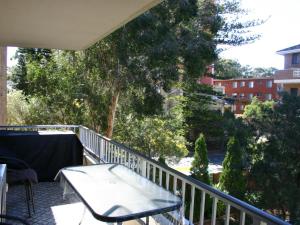 a balcony with a table and chairs and trees at The Breakers 10 in Forster