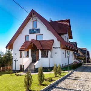 a large white building with a brown roof at Velo Apartamenty in Czorsztyn