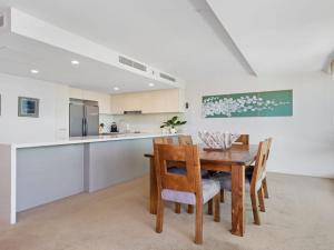 eine Küche und ein Esszimmer mit einem Holztisch und Stühlen in der Unterkunft Strand Beachside 503 in Forster