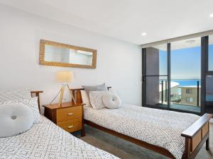 2 Betten in einem Schlafzimmer mit Fenster in der Unterkunft Strand Beachside 503 in Forster