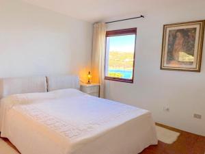 a white bedroom with a bed and a window at Sea & Beach Apartments Porto Cervo Costa Smeralda in Porto Cervo