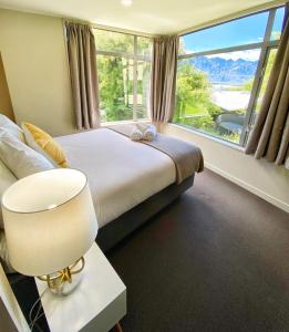 a bedroom with a bed and a large window at Tekau - Modern holiday apartment with lakeview in Queenstown