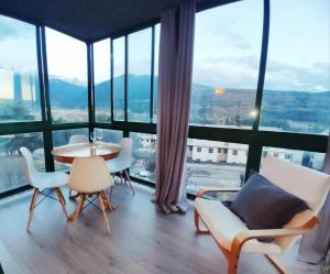 ビリャヌアにあるel rincon de collaradaのテーブルと椅子、大きな窓が備わる客室です。