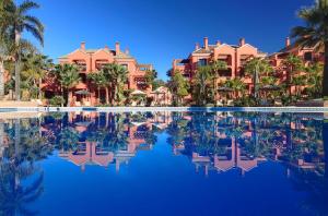 a pool at a resort with palm trees and houses at Vasari Resort in Marbella