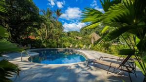 uma piscina com duas cadeiras e um banco em Esquinas Rainforest Lodge em Golfito