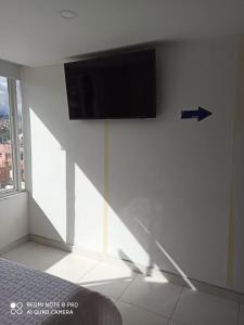 een flatscreen-tv op een witte muur in een kamer bij Hotel Mi Gloria in Tunja