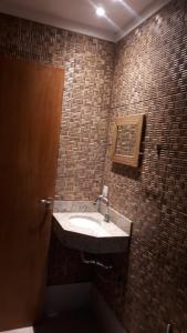 a bathroom with a sink and a brick wall at Pippo Suites Guarujá in Guarujá