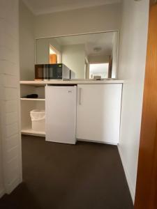 a kitchen with a white refrigerator and a mirror at Top of the Town Motor Inn in Narooma