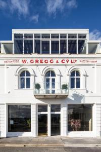 un edificio blanco con un cartel en la parte delantera en The Thomas Gregg Apartments en Dunedin