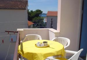 un tavolo con una tovaglia gialla sul balcone di Apartments Nebo - 80 m from beach a Pakoštane