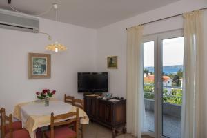 a dining room with a table and a television and a balcony at Apartman Leana in Krk
