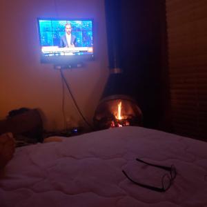 a bedroom with a bed with a television and a fireplace at Cantinho de Mauá in Visconde De Maua
