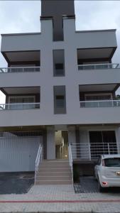 a large white building with a car parked in front at Apartamento in Bombinhas