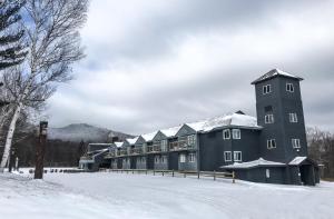 un gran edificio con nieve en el suelo en Mountain Inn at Killington, en Killington